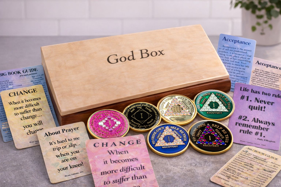 A handcrafted two-tone God Box from Choices Books & Gifts surrounded by recovery medallions and wallet cards, used to hold written worries and prayers that are ready to be set down